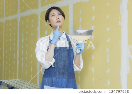 一名婦女正在為石膏板塗膩子 124797938