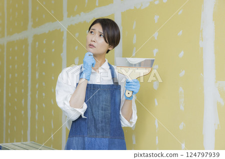 A woman applying putty to plasterboard A woman applying putty to plasterboard 124797939