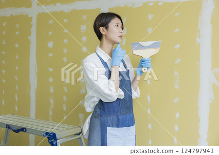 A woman applying putty to plasterboard 124797941