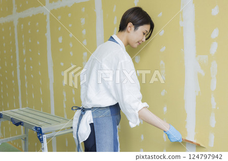 A woman applying putty to plasterboard A woman applying putty to plasterboard 124797942