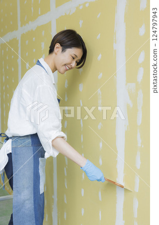 A woman applying putty to plasterboard 124797943