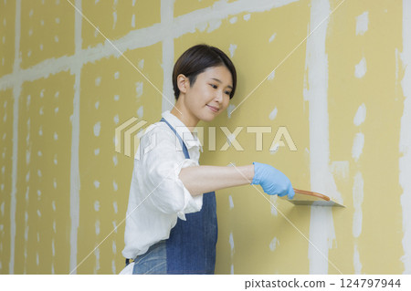 A woman applying putty to plasterboard 124797944