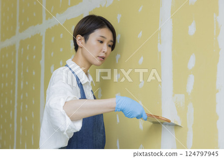A woman applying putty to plasterboard 124797945