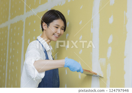 A woman applying putty to plasterboard 124797946