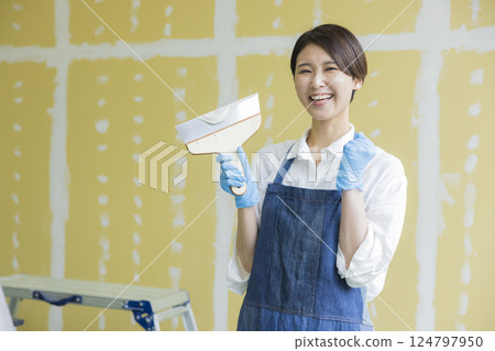 A woman applying putty to plasterboard 124797950