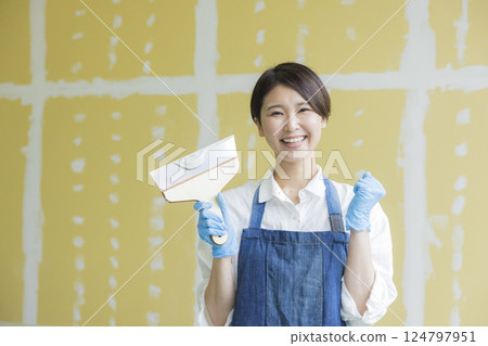 A woman applying putty to plasterboard 124797951
