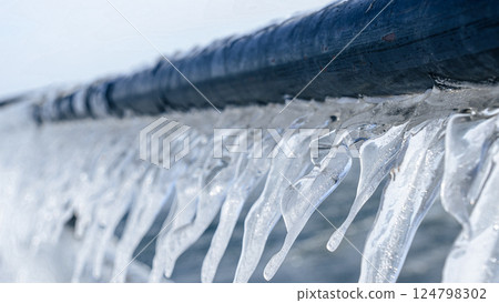 Beautiful Icicles Forming on a Metal Fence with Sunlight Creating a Sparkling Effect in Winter 124798302