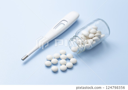 Thermometer and pills on a blue background Thermometer and pills on a blue background 124798356