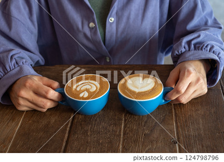 Cropped shot view of woman with a couple cup of hot Cappuccino coffee.  124798796