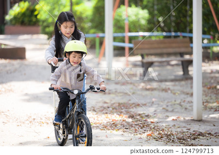 姊姊幫弟弟練習騎腳踏車 124799713