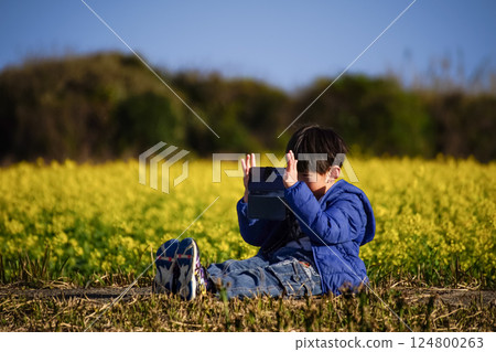 <Flowers and People> A boy taking pictures of rape blossoms with his smartphone 124800263
