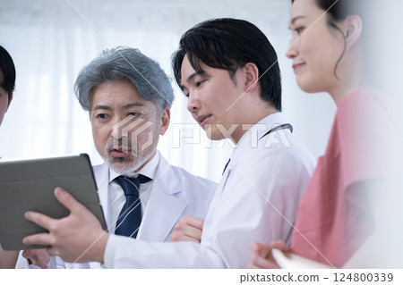 Image of team doctors, supervising doctor and trainee doctor checking medical records and examination status Image of team doctors, supervising doctor and trainee doctor checking medical records and examination status 124800339