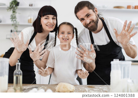 Caucasian parents with young daughter baking in kitchen, enjoying playful moment with flour-covered faces and hands. Captures family bonding, togetherness, and joy through cooking. Caucasian parents with young daughter baking in kitchen, enjoying playful moment with flour-covered faces and hands. Captures family bonding, togetherness, and joy through cooking. 124801388