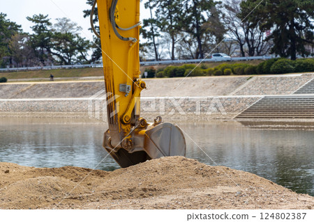 A hydraulic excavator bucket digging soil 124802387
