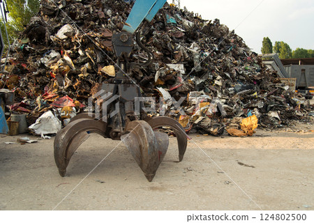 Large tracked excavator working a steel pile at a metal recycle yard. Industrial scrap metal recycling - selective focus, copy space 124802500