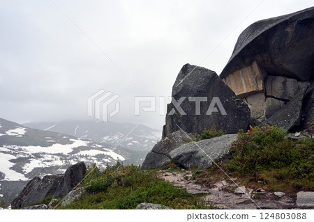 Pathway near rock, misty weather in mountains, natural landscape 124803088