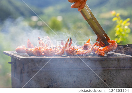 Delicious grilled meat on barbecue grill with smoke and flames in green grass 124803394