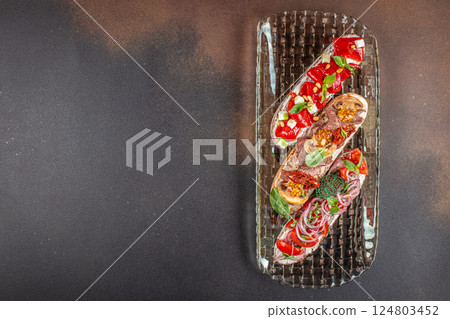 Assorted bruschetta with various toppings. Appetizers with Italian antipasti snacks on a dark background. top view. copy space for text Assorted bruschetta with various toppings. Appetizers with Italian antipasti snacks on a dark background. top view. copy space for text 124803452