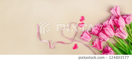 Ribbon in shape of heart with tulips flowers bouquet on a beige background. Mothers Day, birthday celebration concept. Copy space Mockup 124803577