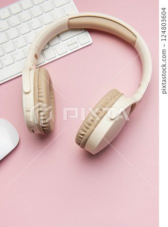 Wireless headphones, keyboard and mouse lying on pink table Wireless headphones, keyboard and mouse lying on pink table 124803604