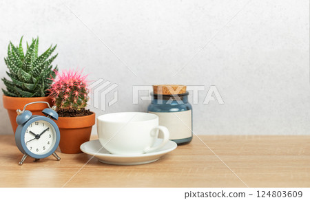 Coffee cup, alarm clock and cacti creating relaxing morning atmosphere on desk 124803609