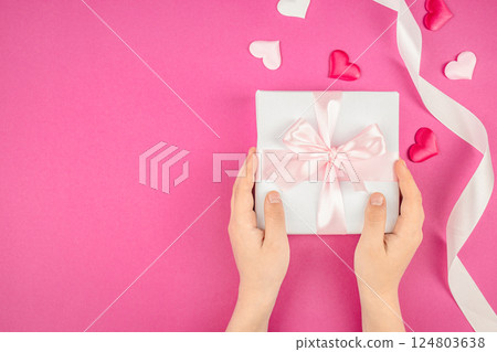 Child holding a gift box with ribbon beautiful tulips on pink background. Top view, close-up. Happy mother's day Child holding a gift box with ribbon beautiful tulips on pink background. Top view, close-up. Happy mother's day 124803638