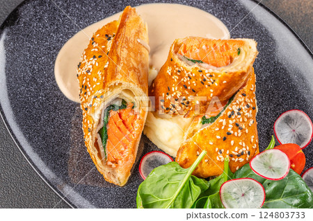 Salmon fillet on leek, baked in puff pastry with creamy sauce and salad. Salmon Wellington Salmon fillet on leek, baked in puff pastry with creamy sauce and salad. Salmon Wellington 124803733