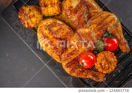 Fried chicken with fresh herbs. Tobacco chicken on a dark background. Georgian dish. top view. copy space. 124803738