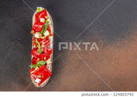 Vegan bruschetta with slices baked red pepper, feta cheese and greens, top view 124803742