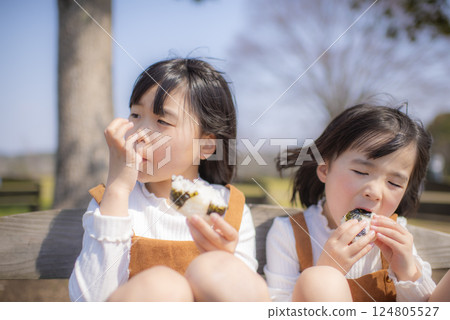 Child eating rice ball in spring park Child eating rice ball in spring park 124805527
