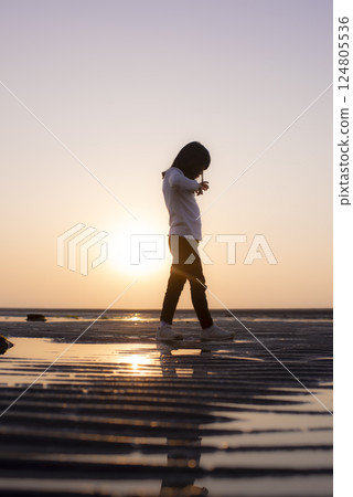 一名女孩在馬塔瑪海灘的日落路上行走 124805536