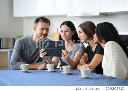 Interracial group of friends checking tablet in a kitchen 124805881