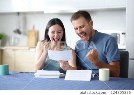Excited interracial couple reading good news on letter 124805886