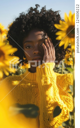 A close up of a person wearing a yellow sweater with their hand on their face. A close up of a person wearing a yellow sweater with their hand on their face. 124806212