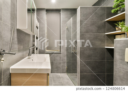 Elegant modern bathroom featuring sleek grey tiles, contemporary fixtures, and a minimalist aesthetic that combines form and function seamlessly. 124806614