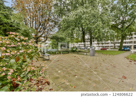 A tranquil urban park featuring lush greenery, benches for relaxation, and walkways, ideal for leisurely strolls amidst nature's beauty. A tranquil urban park featuring lush greenery, benches for relaxation, and walkways, ideal for leisurely strolls amidst nature's beauty. 124806622