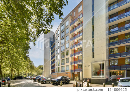 A contemporary apartment complex with a beautiful facade, nestled among lush trees and greenery, showcasing urban architecture and natural beauty. A contemporary apartment complex with a beautiful facade, nestled among lush trees and greenery, showcasing urban architecture and natural beauty. 124806625