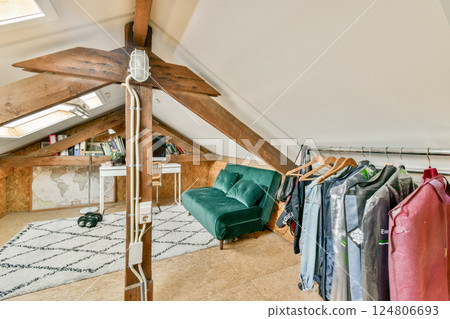 An inviting attic space featuring wooden beams, a cozy seating area, and a stylish clothing rack full of garments. A blend of rustic charm and modern design. 124806693