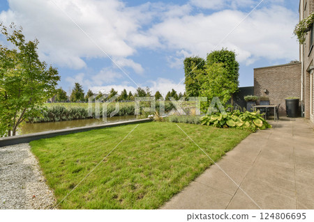 A beautiful outdoor space featuring lush grass, a serene water backdrop, and well-maintained plants creating a tranquil environment for relaxation. A beautiful outdoor space featuring lush grass, a serene water backdrop, and well-maintained plants creating a tranquil environment for relaxation. 124806695