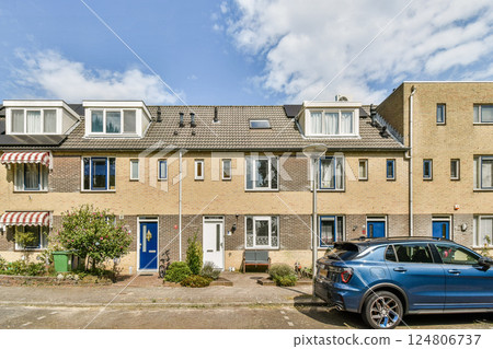 A picturesque view of townhouses lined along a residential street, showcasing unique architecture and surroundings adorned with greenery. 124806737