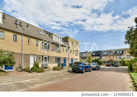 A picturesque view of a cozy residential street featuring charming buildings and vibrant greenery under a clear blue sky. Ideal for neighborhood imagery. 124806825