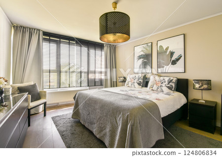 A beautifully designed modern bedroom featuring a comfortable bed, elegant decor, and ample natural light streaming through large windows. A beautifully designed modern bedroom featuring a comfortable bed, elegant decor, and ample natural light streaming through large windows. 124806834