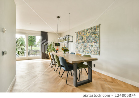A contemporary dining space featuring elegant furniture, an art piece on the wall, and ample natural light streaming through large windows. 124806874