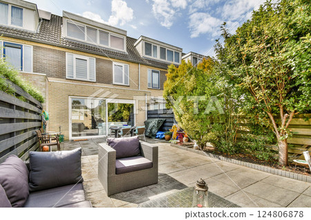 A beautifully arranged outdoor patio surrounded by lush greenery, featuring comfortable seating and decorative plants, creating a serene retreat atmosphere. 124806878