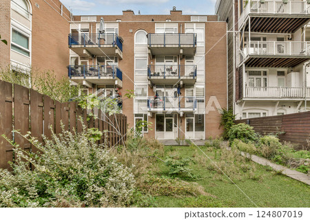 A well-maintained modern apartment complex featuring balconies and greenery. The architecture reflects contemporary design principles. 124807019