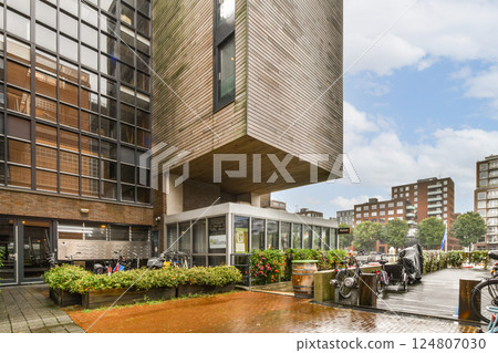 A contemporary building showcasing innovative architecture and urban aesthetic, surrounded by greenery and bicycles, reflecting a vibrant city life. 124807030
