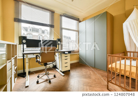 A stylish home office combined with a cozy nursery, featuring a sleek desk, comfortable chair, and modern storage solutions in warm colors. A stylish home office combined with a cozy nursery, featuring a sleek desk, comfortable chair, and modern storage solutions in warm colors. 124807048