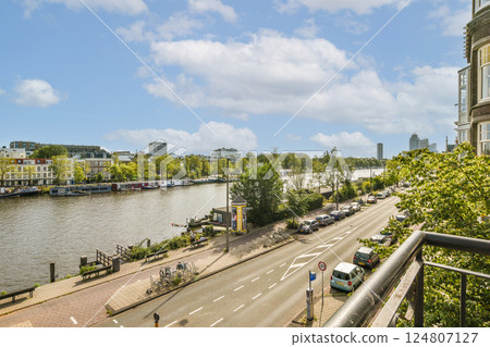 Vibrant riverside scene showcasing trees lining the water and a bustling street, capturing the essence of urban nature blending with daily life. Vibrant riverside scene showcasing trees lining the water and a bustling street, capturing the essence of urban nature blending with daily life. 124807127
