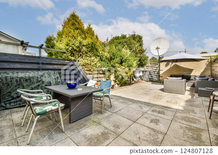 An inviting outdoor patio space featuring modern furniture and greenery, perfect for relaxation or gatherings in a serene environment. 124807128