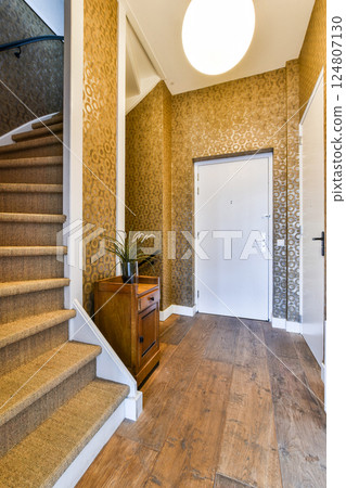 A stylish interior space showcasing a staircase, intricate wall patterns, and modern lighting, creating a warm and inviting atmosphere. 124807130